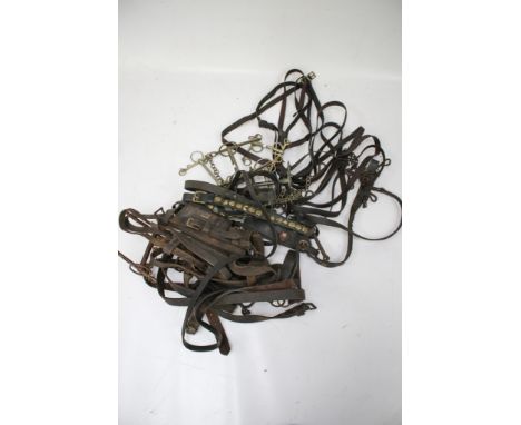 An assortment of antique and vintage horse equipment. Including a harness, brass decorated reins, two bridles etc.