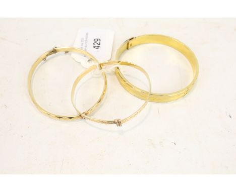 Three gold-plated bangles. Comprising; a facetted hinged bangle marked '1/5th 9ct R.G. GJ Ltd'; a bangle decorated with styli