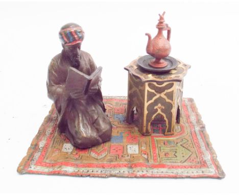 Cold painted bronze model of Arab street vendor on a carpet with coffee pot, carpet measures 14cm x 10cm 