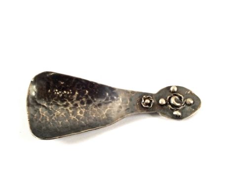 A Silver hammered caddy spoon with scroll work to handle, hallmarks African head and cross