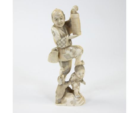 An ivory okimono depicting an old man carrying a lantern, child and barking dog, hollow at the bottem, Japan, end 19th centur