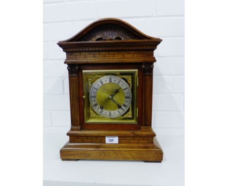 A German beech and walnut cased mantle clock, the domed top with carved frieze above a silvered and brass dial with Roman num