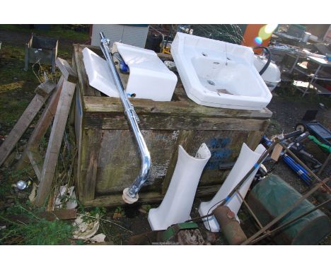 A sink, water cistern, chrome pipe and two pedestals.