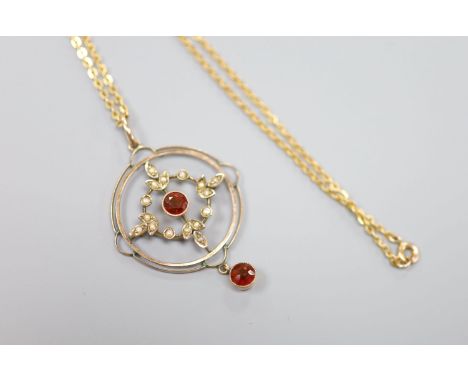 A 9ct, garnet and seed pearl set openwork circular drop pendant, 35mm, on a 9ct chain, 42cm, gross weight 4.9 grams.