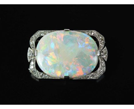 An early 20th century opal and diamond brooch, the large oval opal mounted within diamond set shaped rectangular border, opal