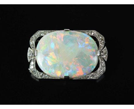 An early 20th century opal and diamond brooch, the large oval opal mounted within diamond set shaped rectangular border, opal