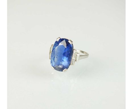 An Art Deco sapphire and diamond ring, the central oval mixed cut sapphire measures approx 15mm x 9.5mm x 5.4mm within four c