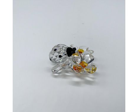 Beautiful faceted ladybug with details in black crystal, it is on top of two flowers with yellow center, giving an extra touc