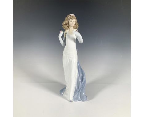 A glossy figure of a woman in an elegant white dress with a blue train, holding up flowers. 1999 Vanguard Figurine. Lladro ba