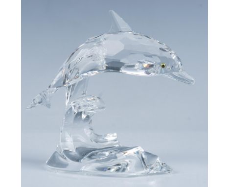 A dolphin with shimmering blue crystal eyes gracefully glides at the crest of a wave. Swarovski backstamp. This item has its 