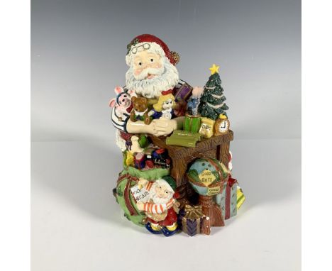 This festive figure depicts Santa Claus leaning on a table, surrounded by an abundance of gifts. A winder located at the bott