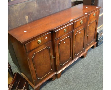 A contemporary breakfront mahogany sideboard, four short drawers, above fielded panel doors, ogee bracket feet 