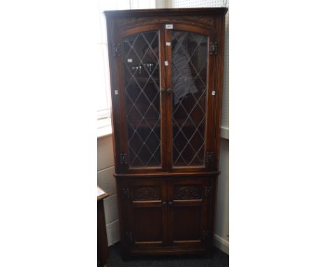 A Jacobean Revival oak corner cupboard, astral glazed cupboard doors enclosing two shelves, above two fielded carved panelled