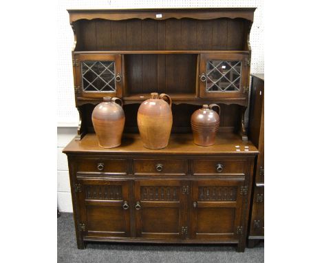 A Jacobean Revival oak dresser, two shelves, the central shelf flanked by two two astral glazed cupboard doors, the projectin
