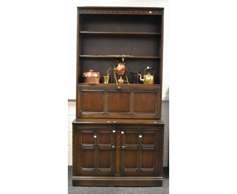 An Ercol (red label) dark oak dresser, three shelves above fall front door, the projecting base with two cross banded panelle