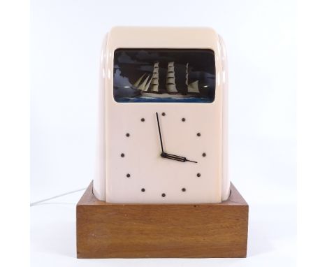 A Vitascope pink Bakelite-cased clock, circa 1930s, with rolling ship automaton, on later wooden stand, overall height includ