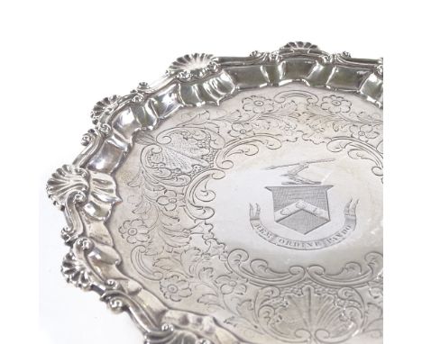 A George II circular silver salver, scalloped foliate and shell rim with floral engraved centre and hoofed feet, engraved mot