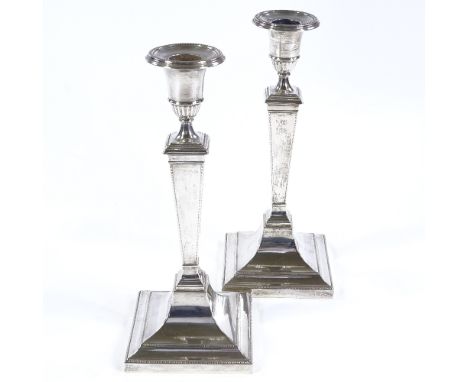 A pair of George V silver table candlesticks, square form with stepped base, reeded border and removable sconces, by Hawkswor