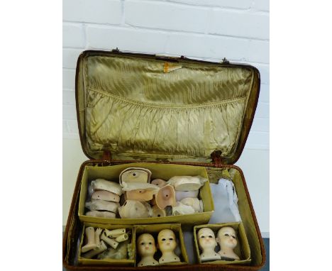 A vintage suitcase containing a collection of bisque doll heads, limbs and other body parts (a lot) 