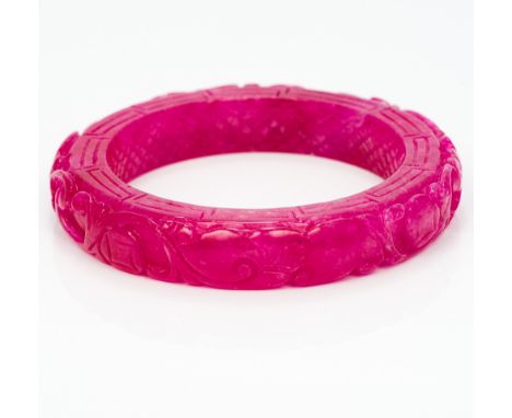 A Chinese ruby coloured jade bangleWith all over scrolling carved decoration.  8 cm diameter.  CONDITION REPORTS: Generally i