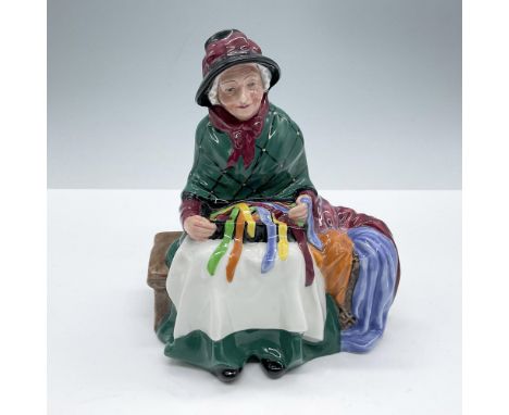 Features an old lady sitting on a bench, with a box of colorful ribbons and silks. She wears a dark green skirt and shawl. Ro