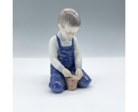 Charming porcelain figurine depicting a young boy playing with a pail. Finished in glossy underglaze technique with subtle hu