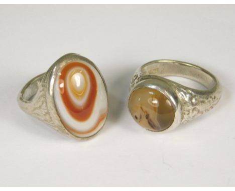 SILVER RINGS. Two silver rings hand made by John Simpson (St. Ives), each set with agate. Approx. 21g. Size K &amp; O.