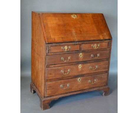 A George III Oak Bureau, the fall front enclosing a fitted interior above two short and three long graduated drawers with bra