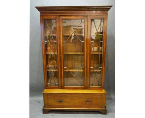 A Mahogany and Satinwood Crossbanded Bookcase, the moulded cornice above astragal glazed door flanked by similar panels enclo