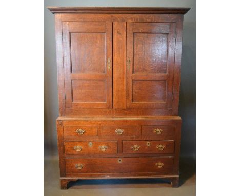 A George III Oak Bacon Cupboard, the moulded cornice above two panel doors, the lower section with an arrangement of simulate