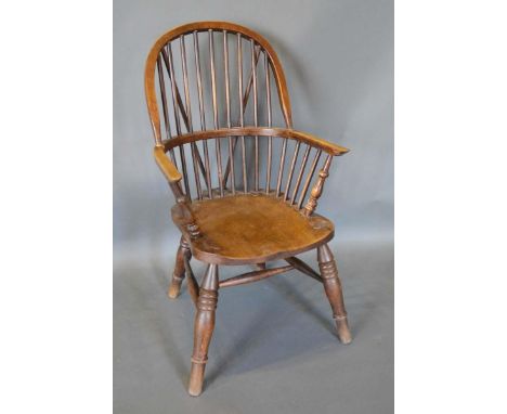 An Early 19th Century Elm Windsor Armchair with a spindle back above a panel seat raised upon turned legs with stretchers 