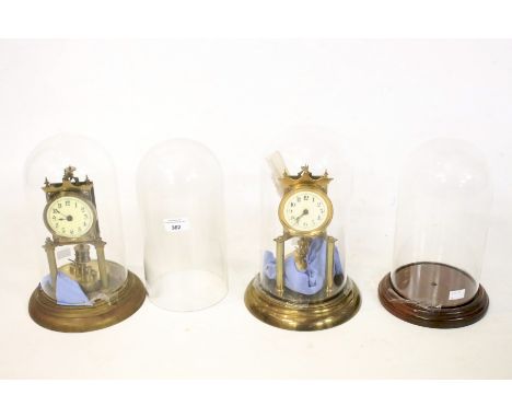 Two anniversary clocks under glass domes and two further glass domes. Both clock with enamel dials with Aracbic numerals and 