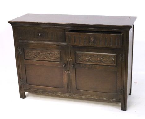 A contemporary oak sideboard. Two drawers positioned over a pair of panelled doors, opening to reveal a single shelf, raised 