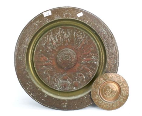 An assortment of metalware. Including a brass coal bucket, embossed copper chargers, warming pan, fire tools, etc