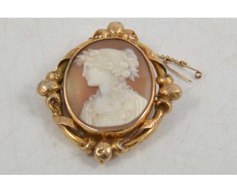 An oval carved shell cameo brooch, portrait of a girl with flowers in her hair, 40x35mm, in a yellow metal frame with chased 