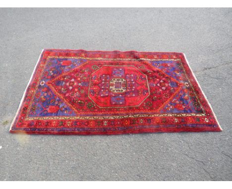 A LARGE VINTAGE WOOLLEN RUG, MAINLY RED GROUND 210 X 128 cm