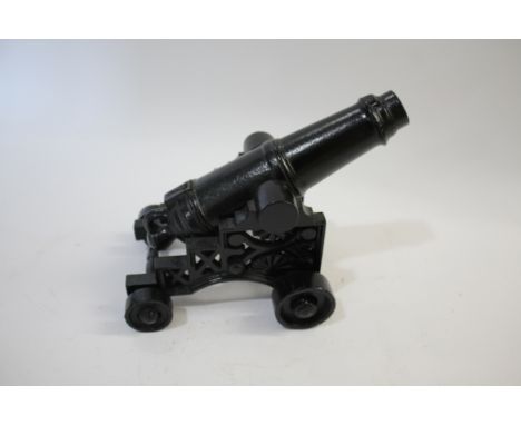 CAST IRON MODEL CANNON a reproduction cast iron model of a cannon, mounted on a carriage with wheels. 27cms long overall
