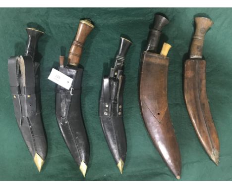 FIVE SIMILAR KUKRI KNIVES AND SCABBARDS. A Kukri knife with wooden scabbard with 'chip-carved' decoration, the knife with sha