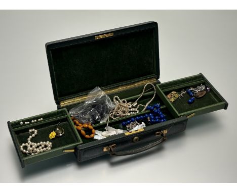 A 1920s green leather weekend travelling jewellery case with green velvet-lined interior containing a collection of costume j