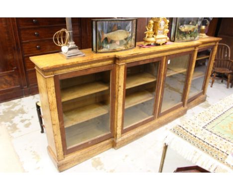 Large Victorian light oak breakfront bookcase with adjustable shelves enclosed by four glazed doors on plinth base