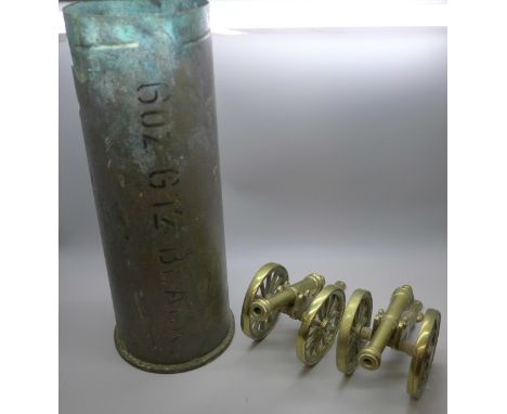 A brass shell case and two brass model cannons 