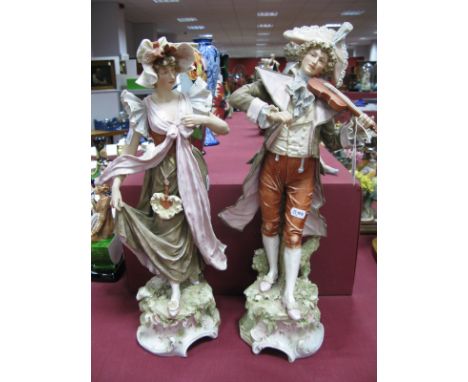 A Pair of Royal Dux Figures, modelled as XVIII Century courtiers, he playing the violin, she dancing, upon scrolling circular