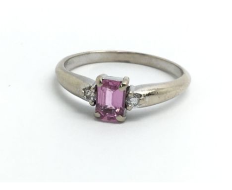 An 18ct white gold ring set with central pink sapphire and two diamonds, ring size approx M