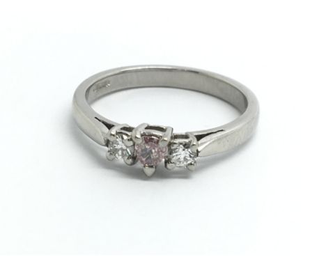 A platinum ring set with central pink diamond and two more diamonds, approx L