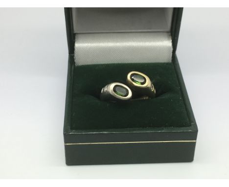 A modern design ring set with two green stones and small diamonds, approx 6.9g and approx size K.
