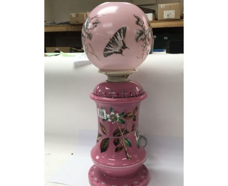 A Victorian pink glass oil lamp enamel decorated with flowers and foliage.