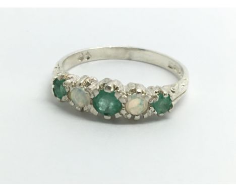 A silver ring set with emeralds and opals