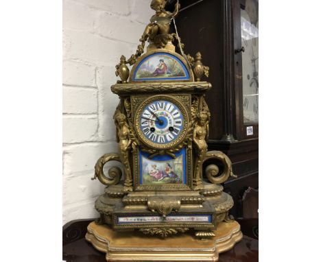 A gilt mantel clock the top surmount with cherub inset with porcelain panels. 53 cm