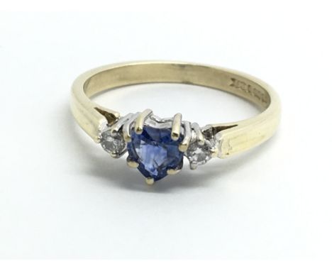 An 18ct yellow gold ring set with central heart shaped sapphire and two diamonds, approx size K