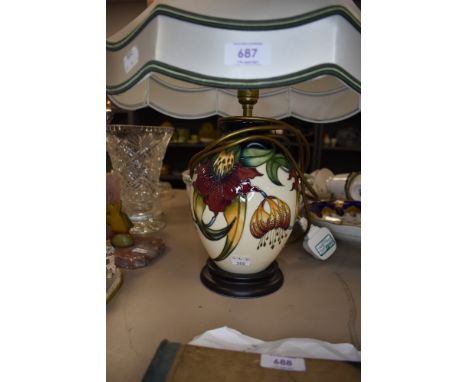 A Moorcroft Anna lily table lamp with shade having lily design in green,red and ochre on cream ground.
